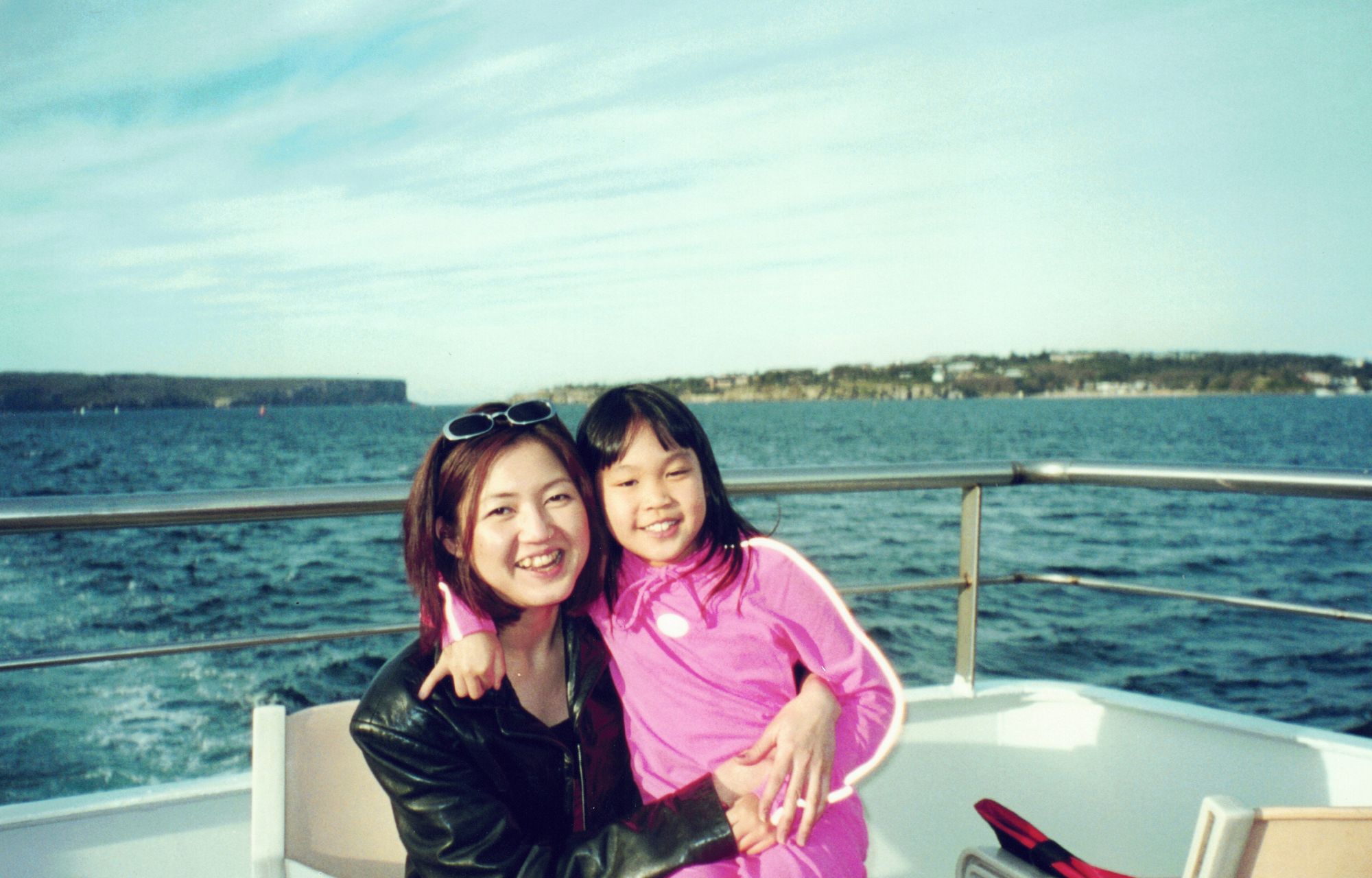My mother holding me on a boat deck, open sea behind
