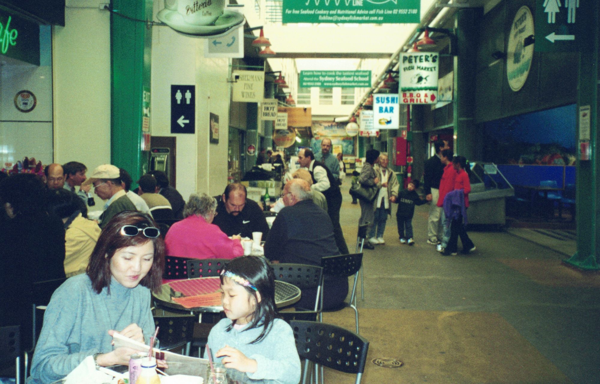 My mother and me at a table in a busy covered food arcade