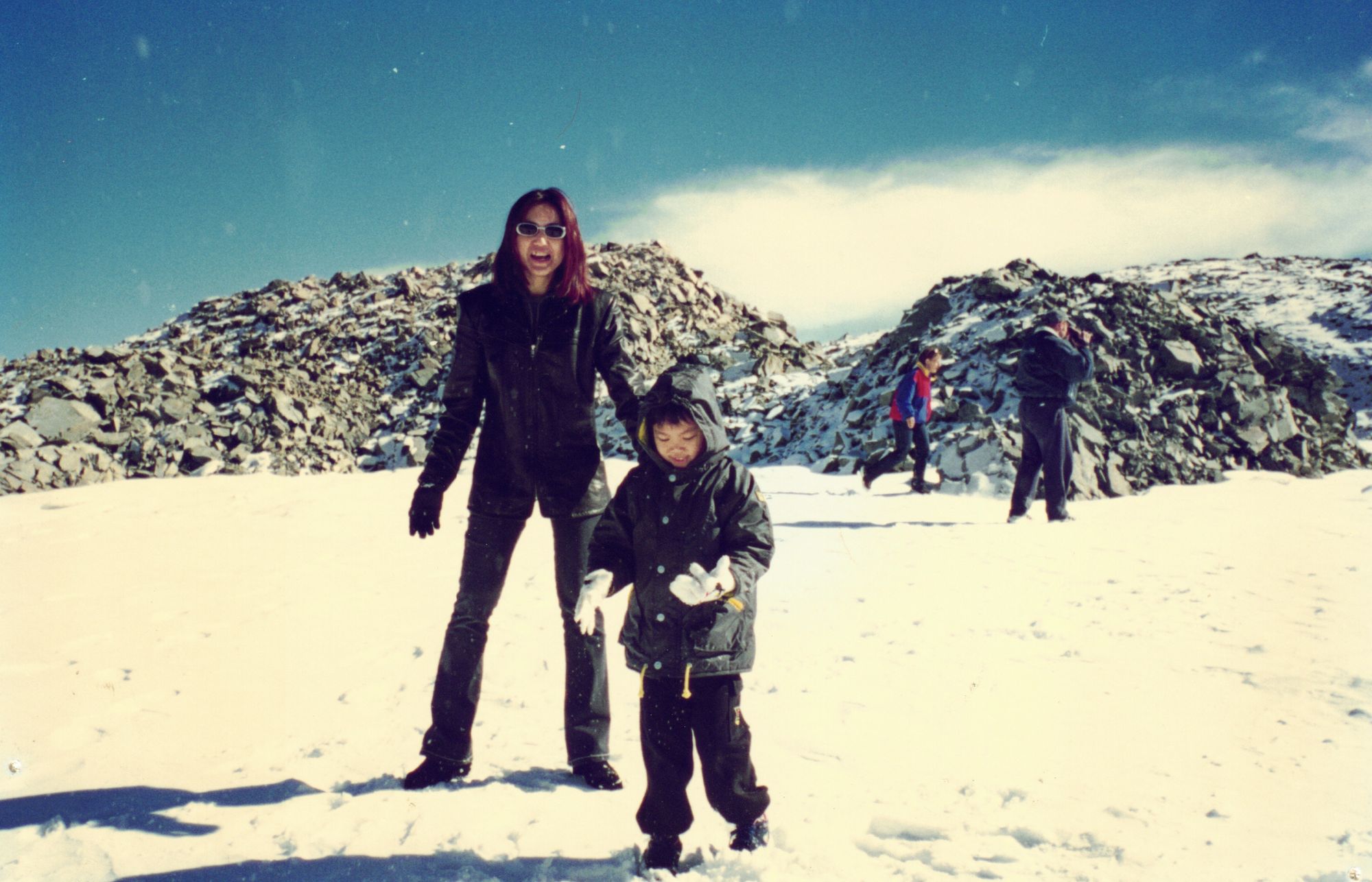 My mother and me playing in snow between dark rock ridges