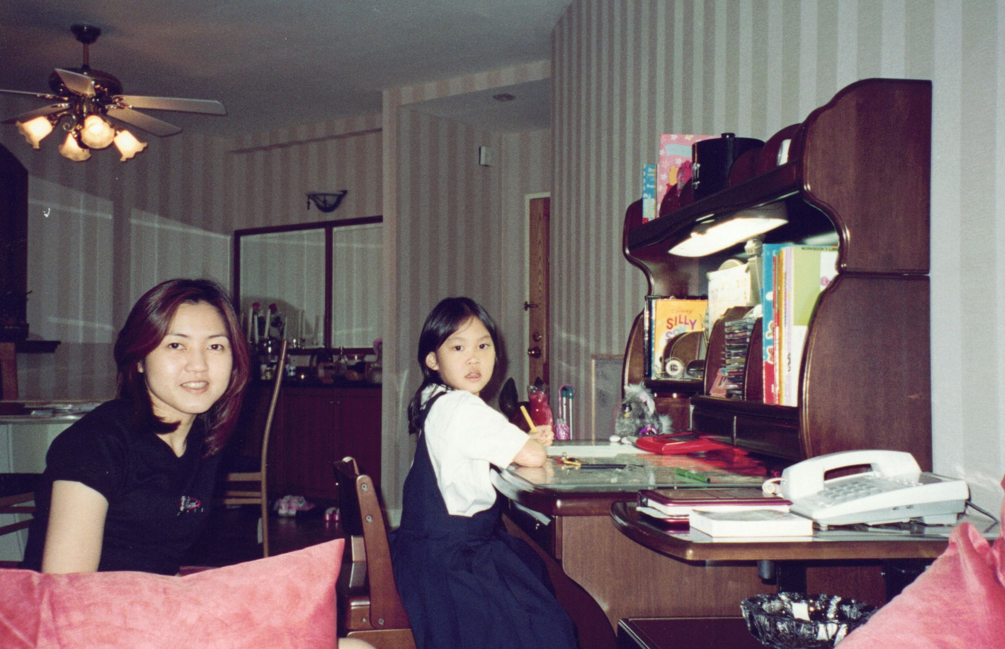 Me in my ICS uniform, writing at a wooden desk beside my mother, a telephone and papers around us