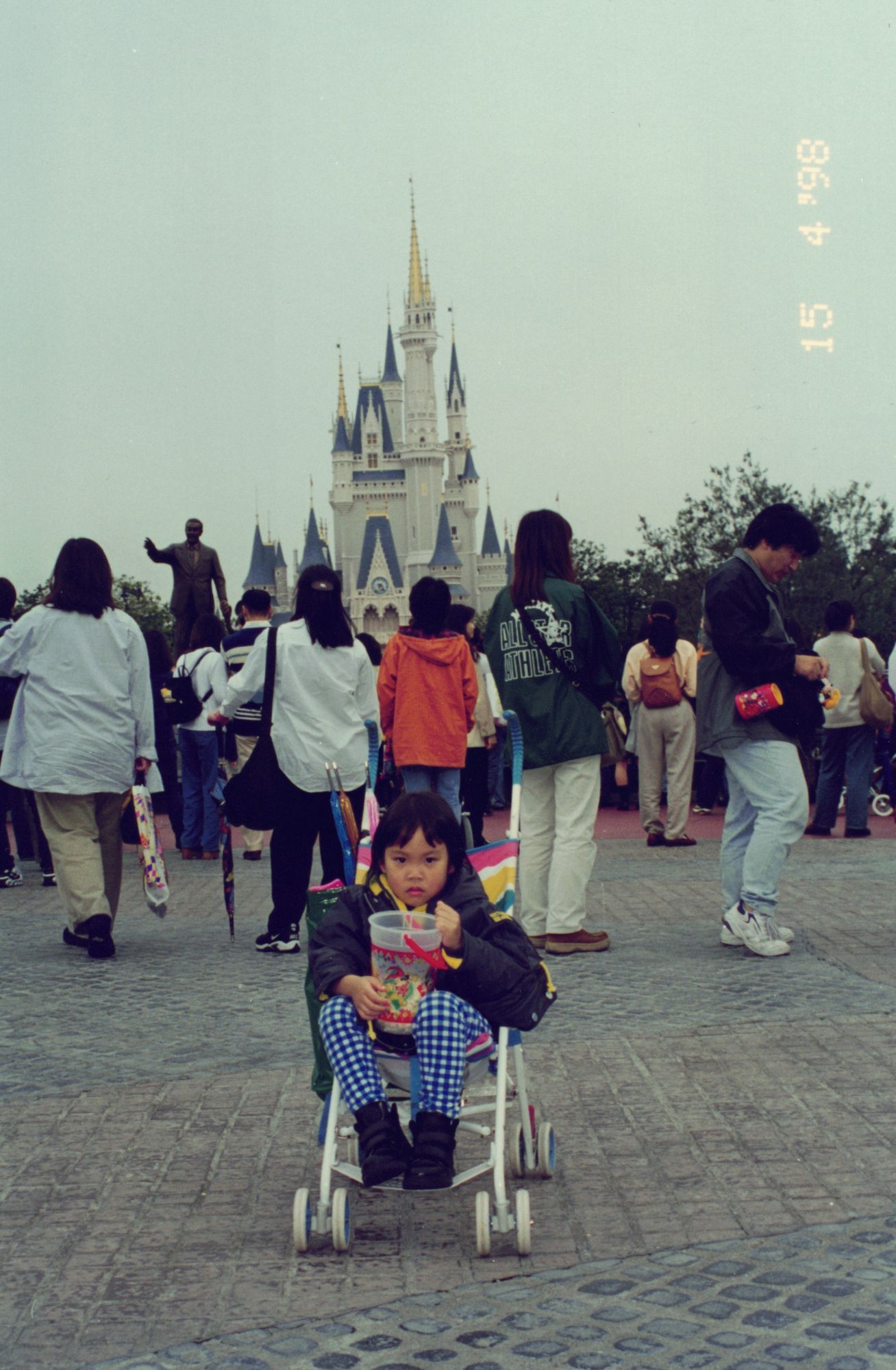 Me small in a stroller on a wide plaza, a fairy-tale castle behind