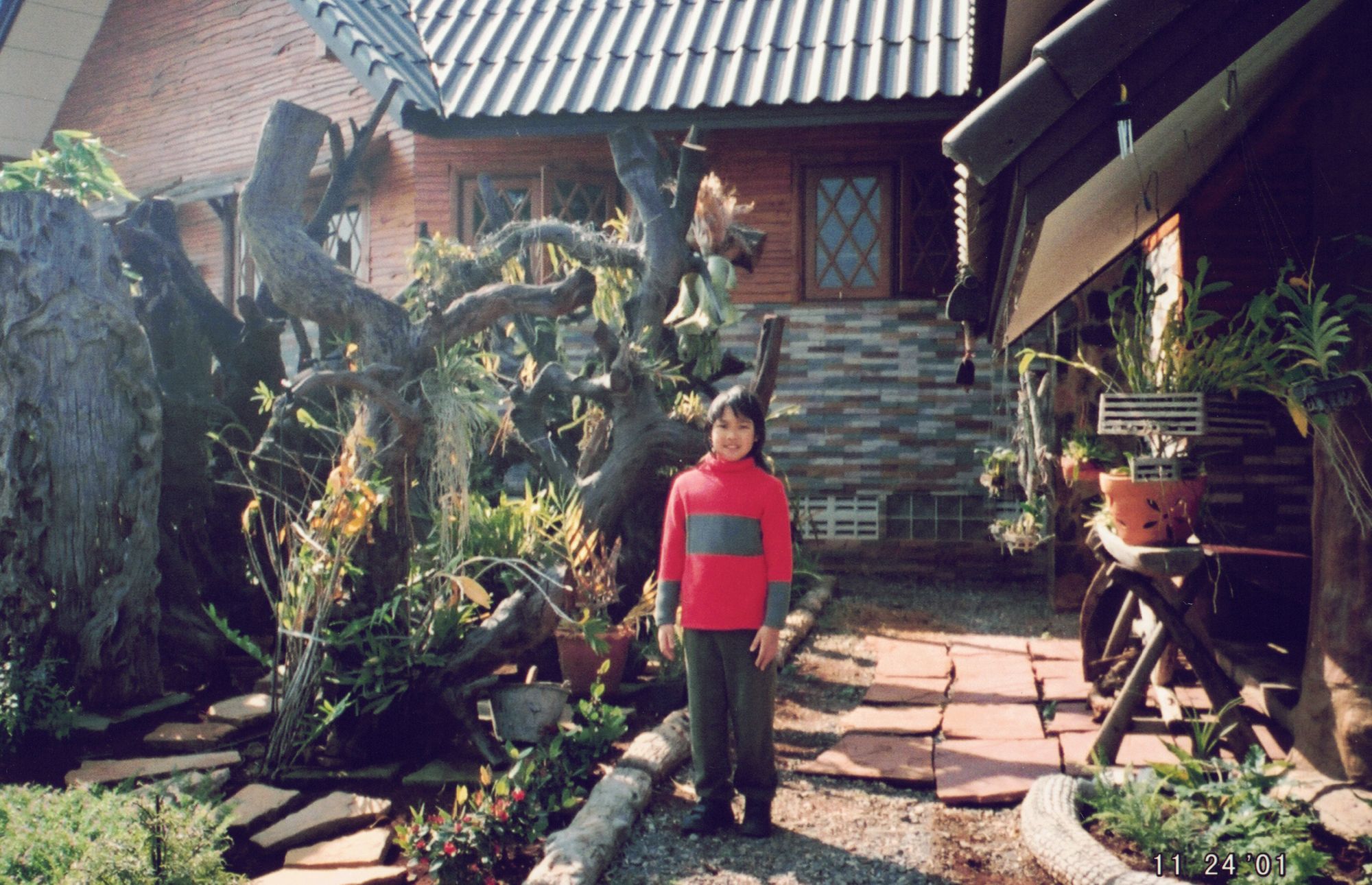Me in a red jumper in the garden of a wooden house