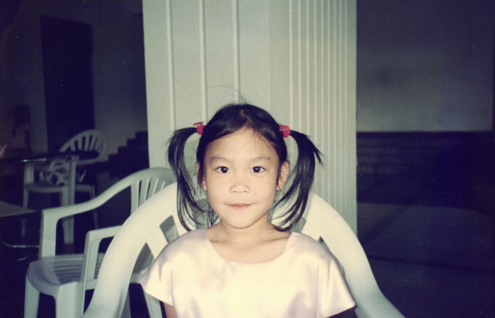 An indoor portrait of me with pigtails, in a pale dress