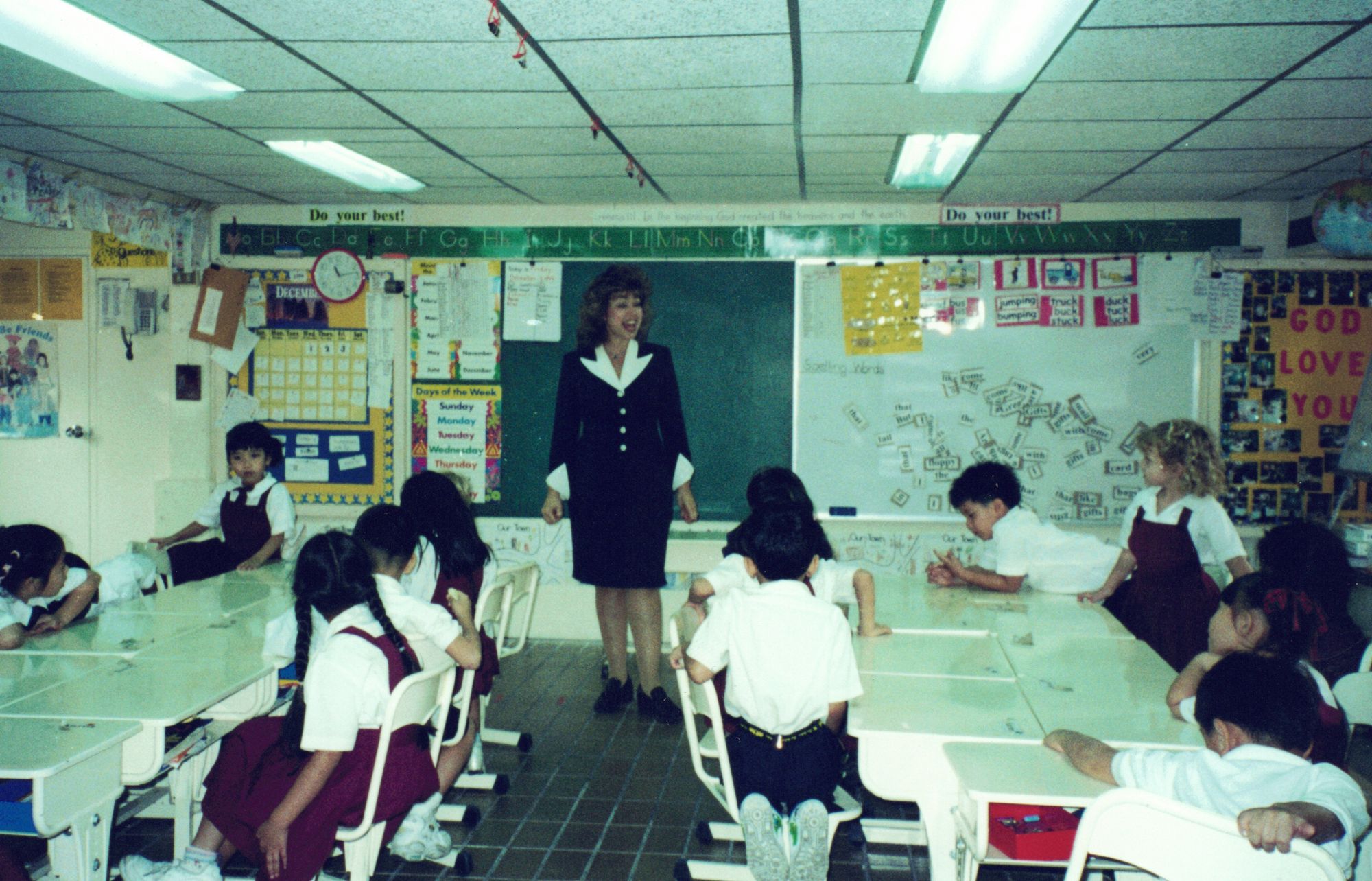My kindergarten classroom in Bangkok — Ms. Keila standing among the children at their white tables