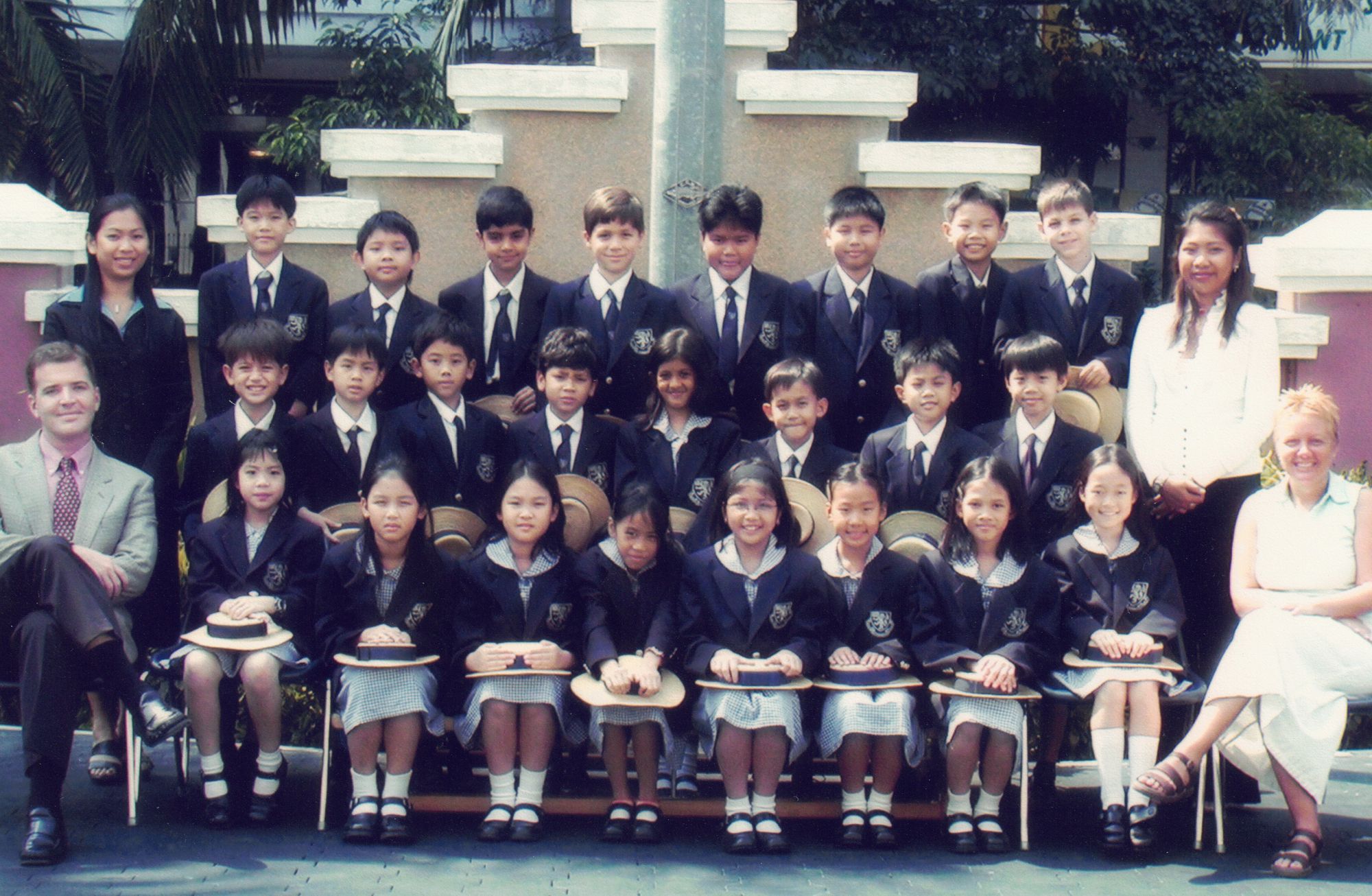 My Year 4 class photograph at Harrow’s original Bangkok Garden campus — rows of children in blazers, boaters on knees, Mr Roche and the other teachers at each side
