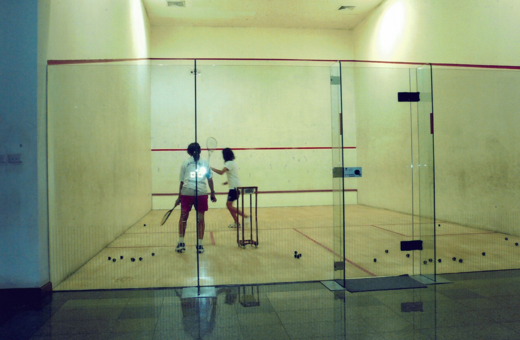 Two children mid-rally on a squash court