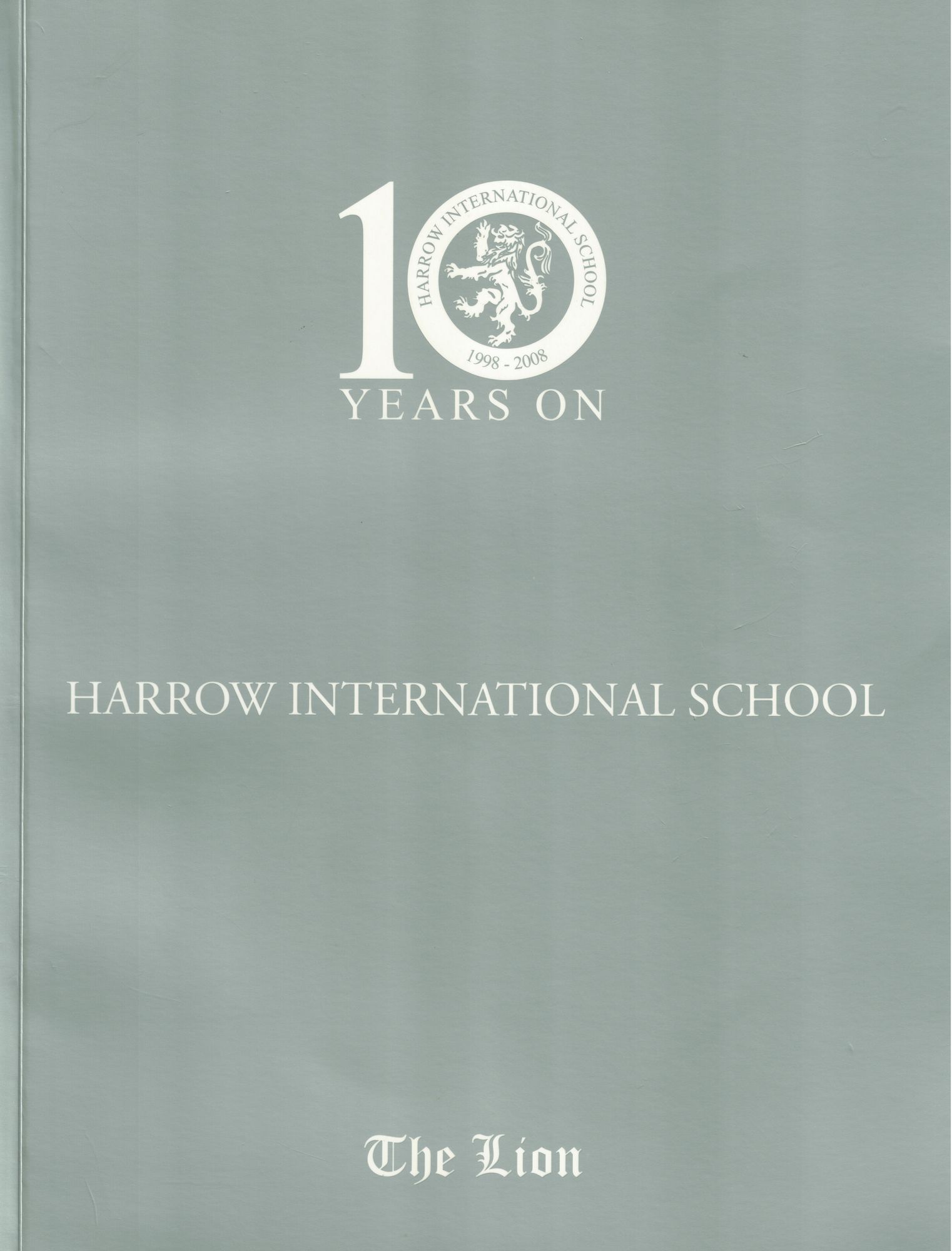 The Lion, the 2007–2008 Harrow International School yearbook — a grey cover marked 10 Years On, 1998–2008, with the school crest
