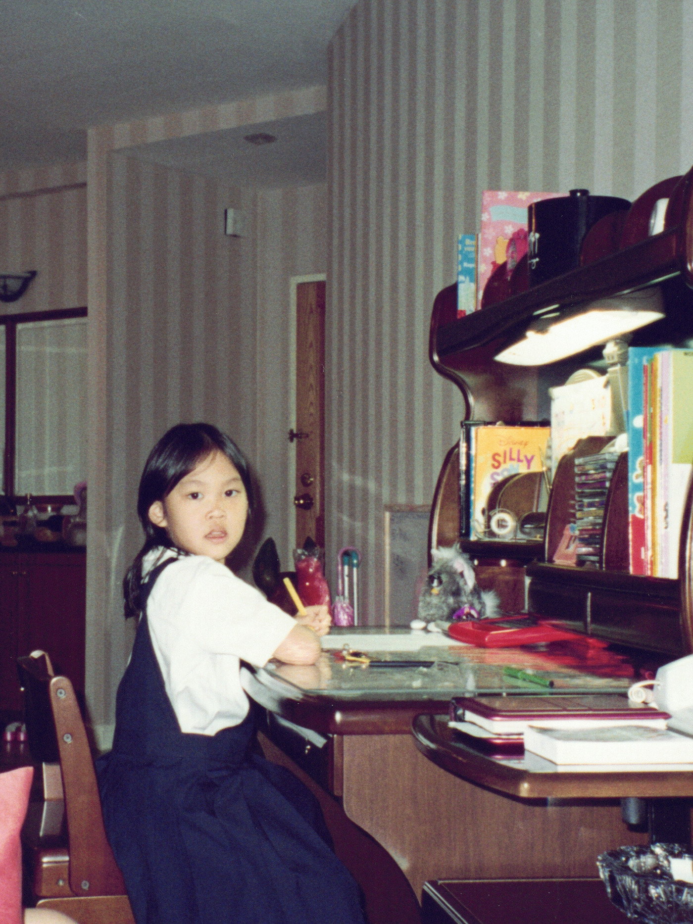 Me in my school uniform at my desk in Bangkok, the bookshelf beside me